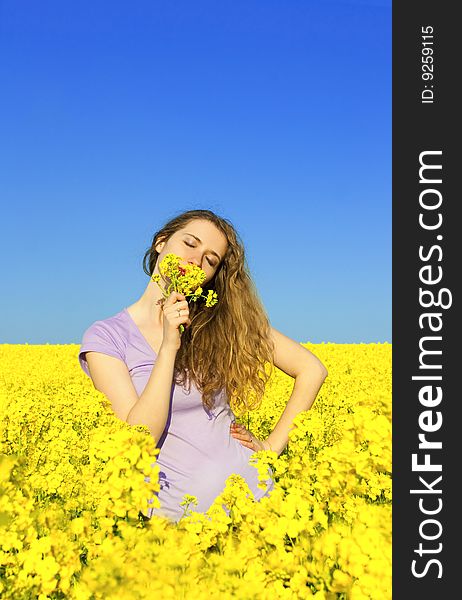 Woman in rape(canola) field smelling flowers. Woman in rape(canola) field smelling flowers