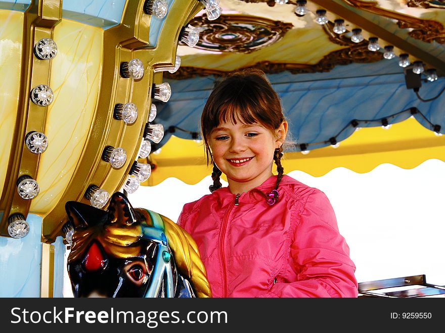 The child smiles nicely. She rolls on the carousel in the Children's Park. The child smiles nicely. She rolls on the carousel in the Children's Park.