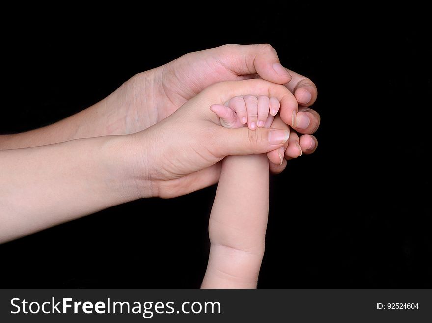 The hands of the father and the mother holding the hand of the child. The hands of the father and the mother holding the hand of the child.