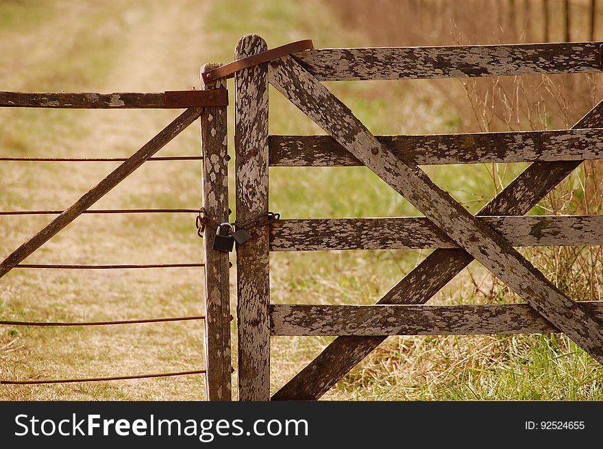 An old fence with a gate on a rural road. An old fence with a gate on a rural road.