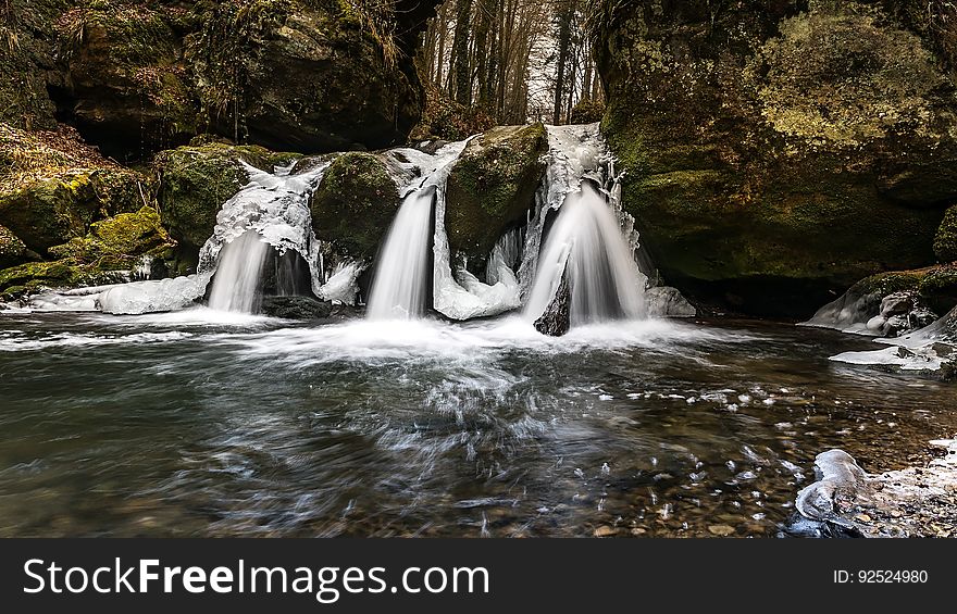 A triple waterfall flowing into a creek.