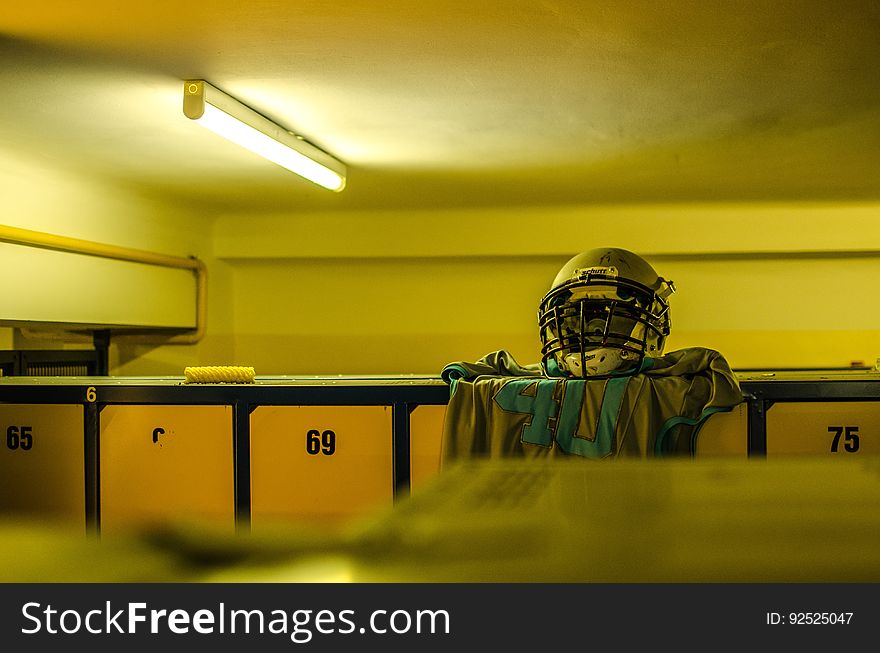A locker room with a jersey and a helmet resting on top of a locker.