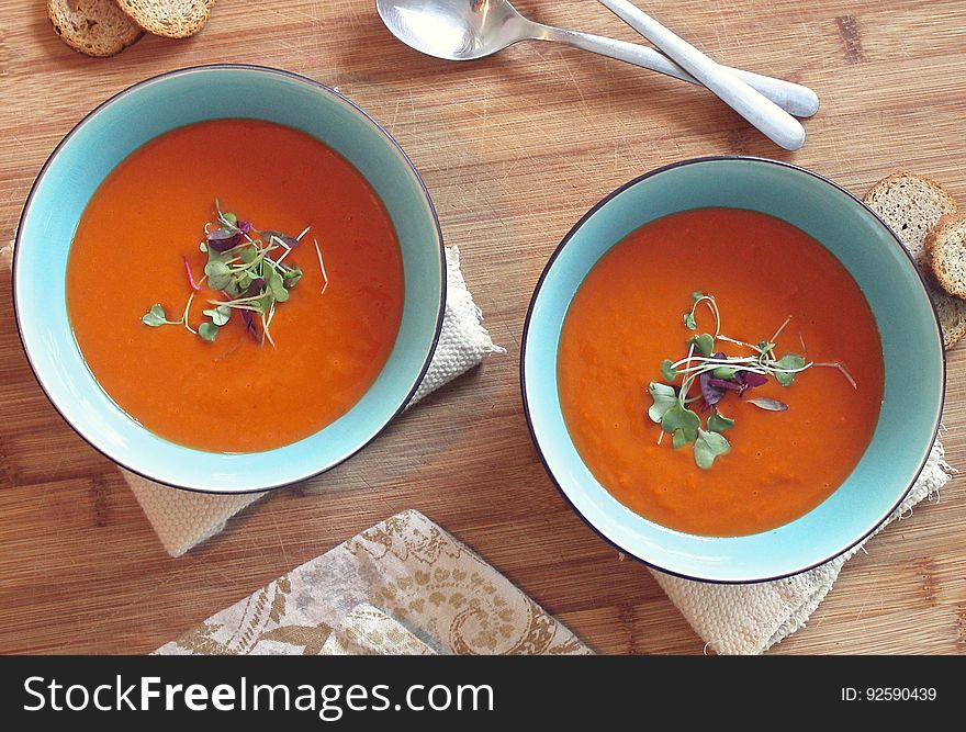 Bowls of creamy tomato soup on a wooden table.