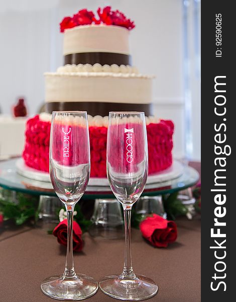 A pair of champagne glasses for the bride and the groom and a wedding cake. A pair of champagne glasses for the bride and the groom and a wedding cake.