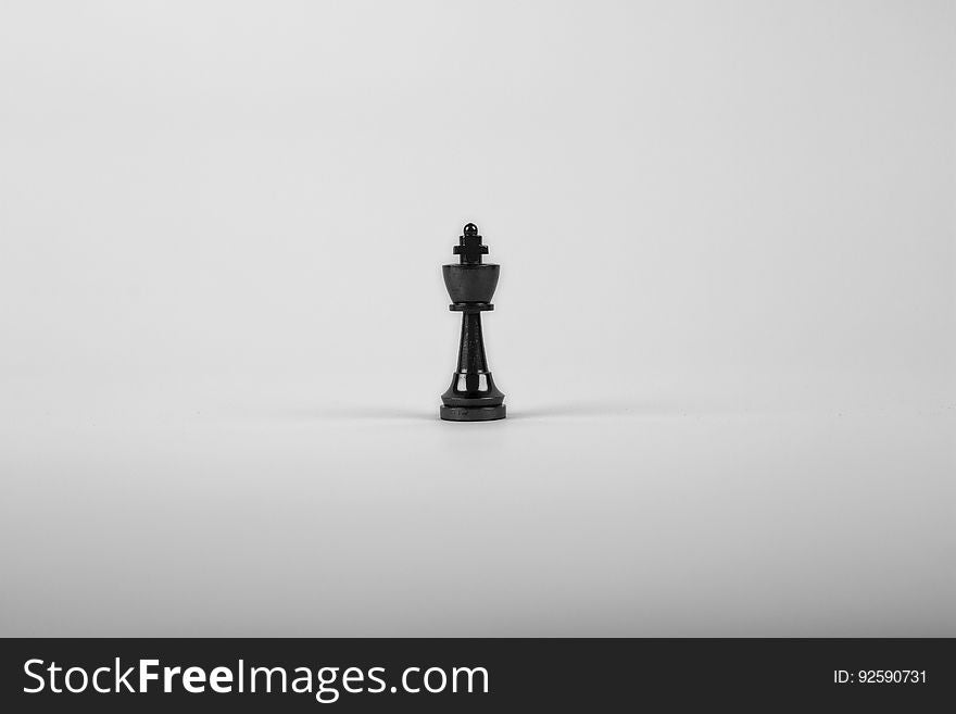 Lone black chess king surrounded by white space. Lone black chess king surrounded by white space.