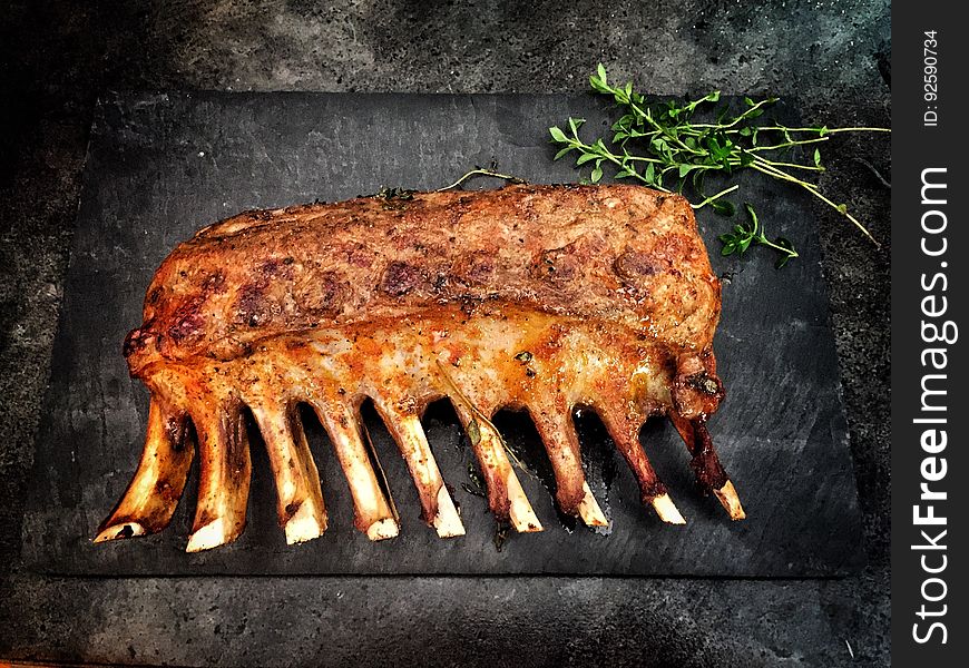 Rib of beef cooking over a barbecue, looking brown and well done, with sprigs of herb (rosemary or thyme) placed behind. Rib of beef cooking over a barbecue, looking brown and well done, with sprigs of herb (rosemary or thyme) placed behind.