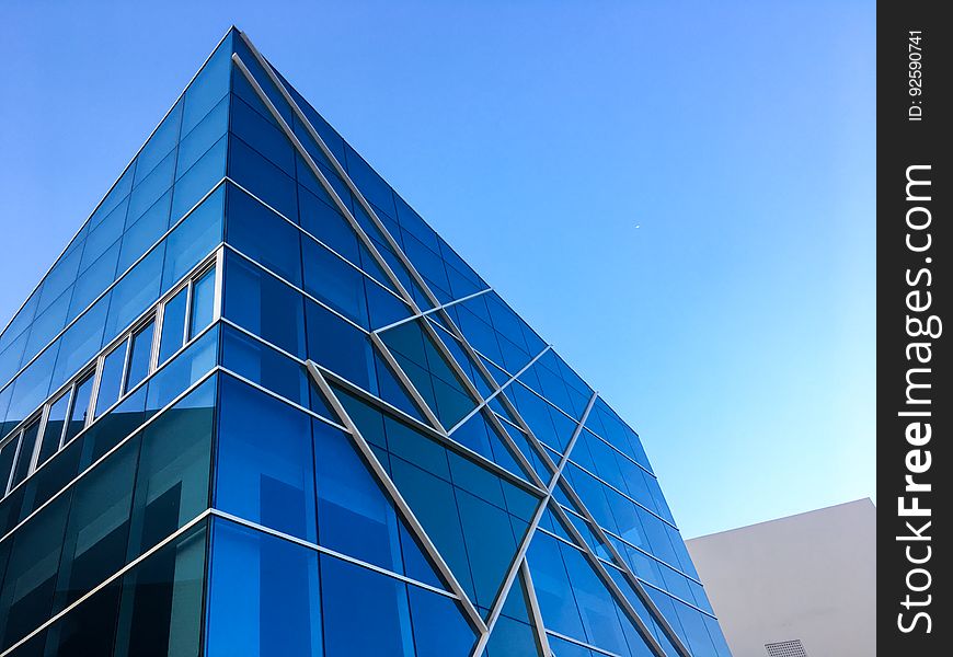 Example of a building with steel, glass and concrete construction which does not conform to simple rectangular panels but incorporates triangular sections, diagonal lines and off axis squares and reflects blue light from the sky. Example of a building with steel, glass and concrete construction which does not conform to simple rectangular panels but incorporates triangular sections, diagonal lines and off axis squares and reflects blue light from the sky.