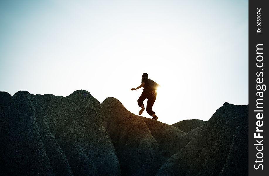 A hiker walking on rocks against the blue sky. A hiker walking on rocks against the blue sky.