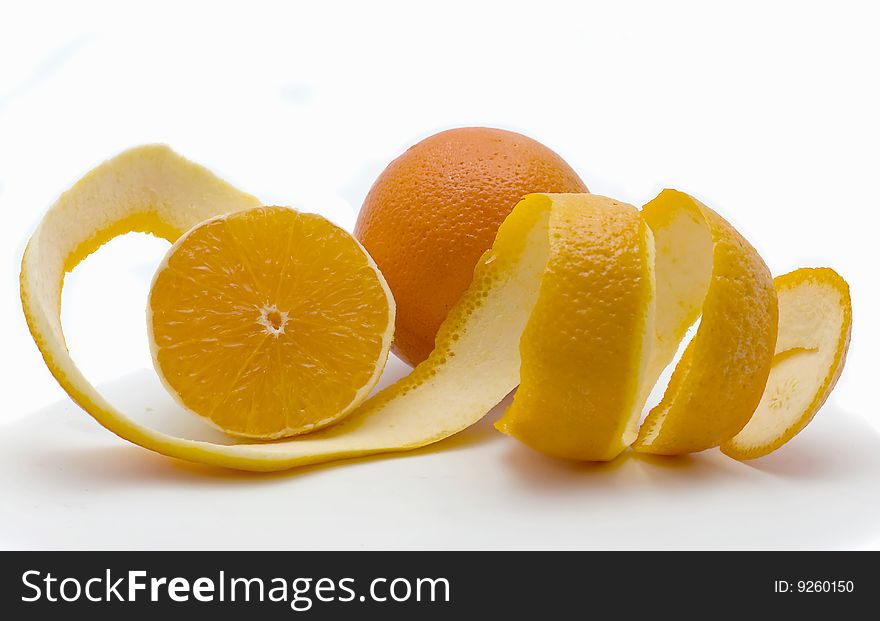 Whole both half of orange and a peel in the form of a spiral on a white background