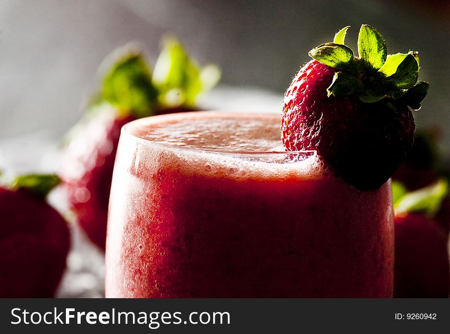 Backlit glass of freshly made strawberry smoothie. Backlit glass of freshly made strawberry smoothie