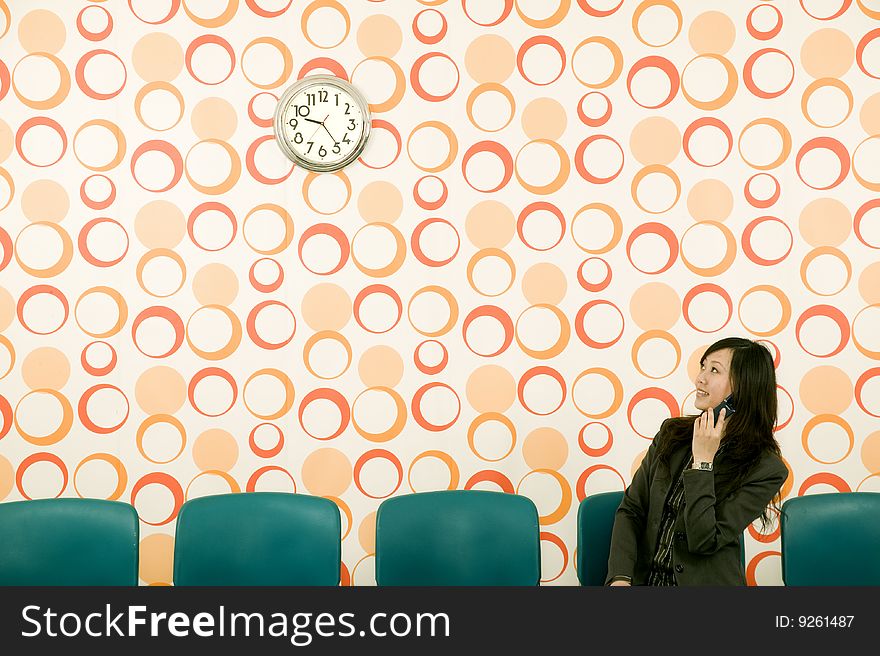 Woman checking the time in a retro wallpapered waiting room. Woman checking the time in a retro wallpapered waiting room.