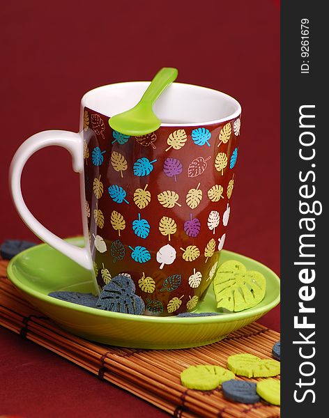 Cup of coffee in brown cup on green plate and leaves motive as decoration