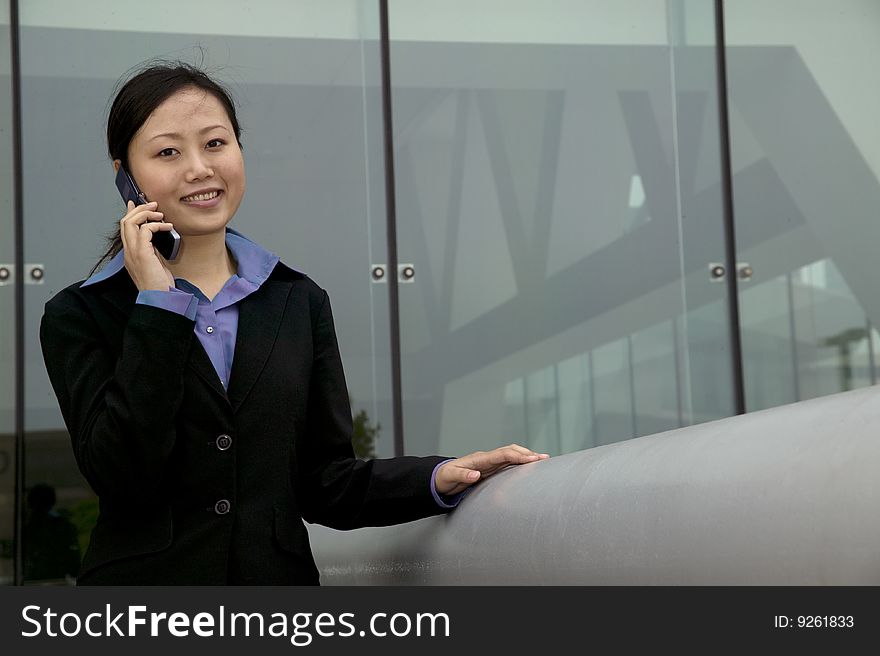 Young Asian businesswoman talking on her cellphone on concrete stairs. Young Asian businesswoman talking on her cellphone on concrete stairs.