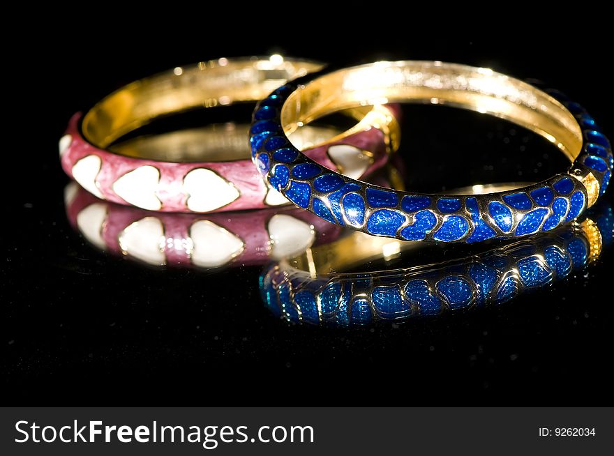 Colorful bangles reflected on black surface