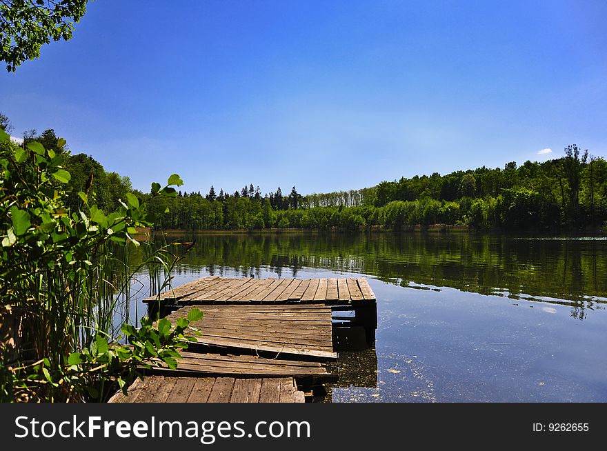 Landscape with lake, forest, footbridge and blue sky. Landscape with lake, forest, footbridge and blue sky