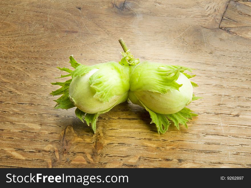 Pair of unripe hazelnuts on wooden table