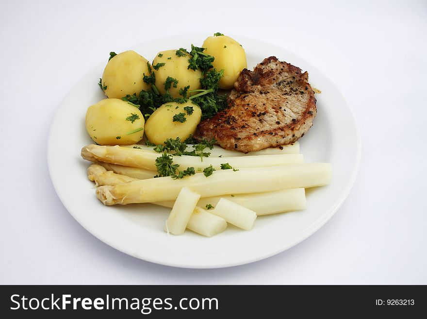 Dish with asparagus, potatoes and a chop of meat. Dish with asparagus, potatoes and a chop of meat