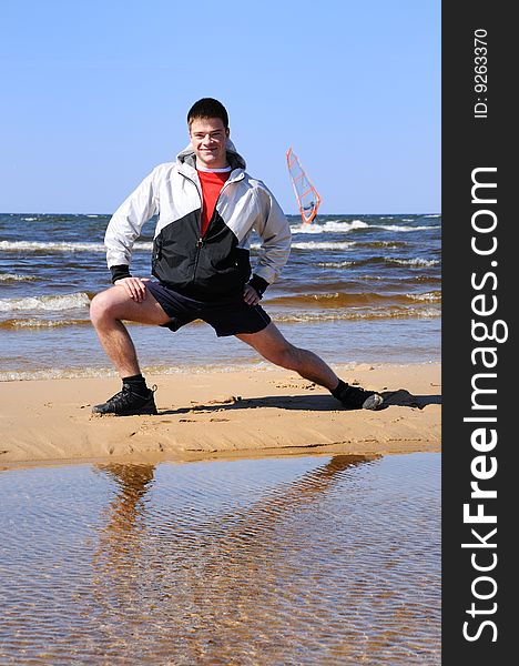 Young man doing exercise at beach, summer time
