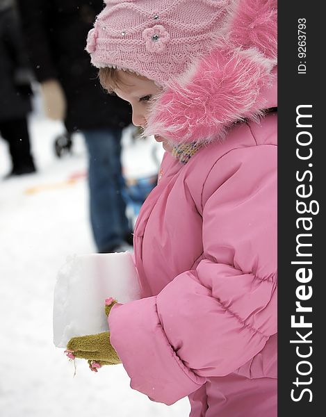 The little girl holds a pyramid from snow