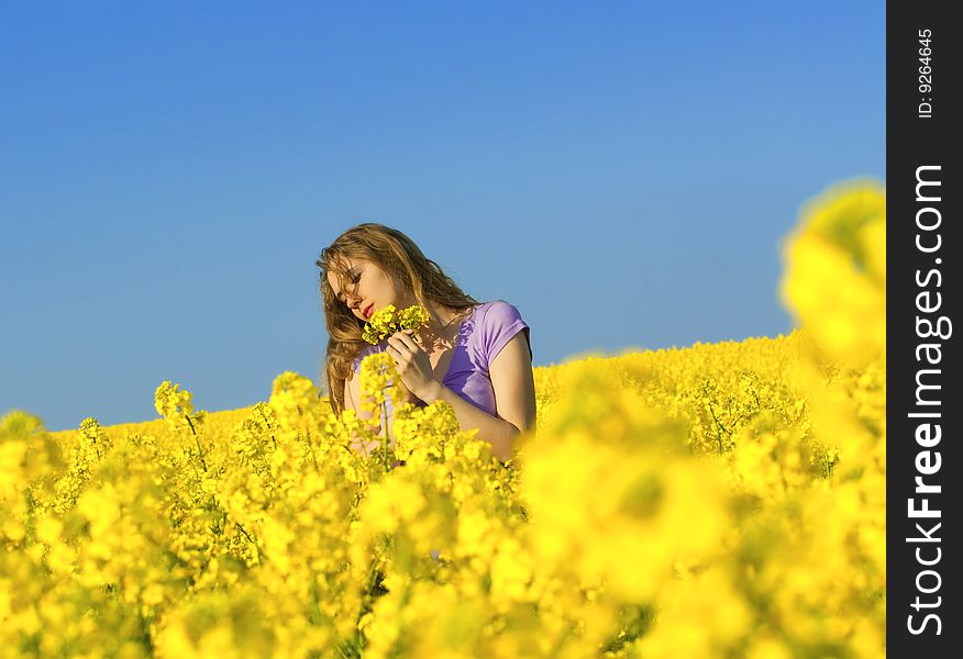 Woman in rape(canola) field smelling flowers. Woman in rape(canola) field smelling flowers