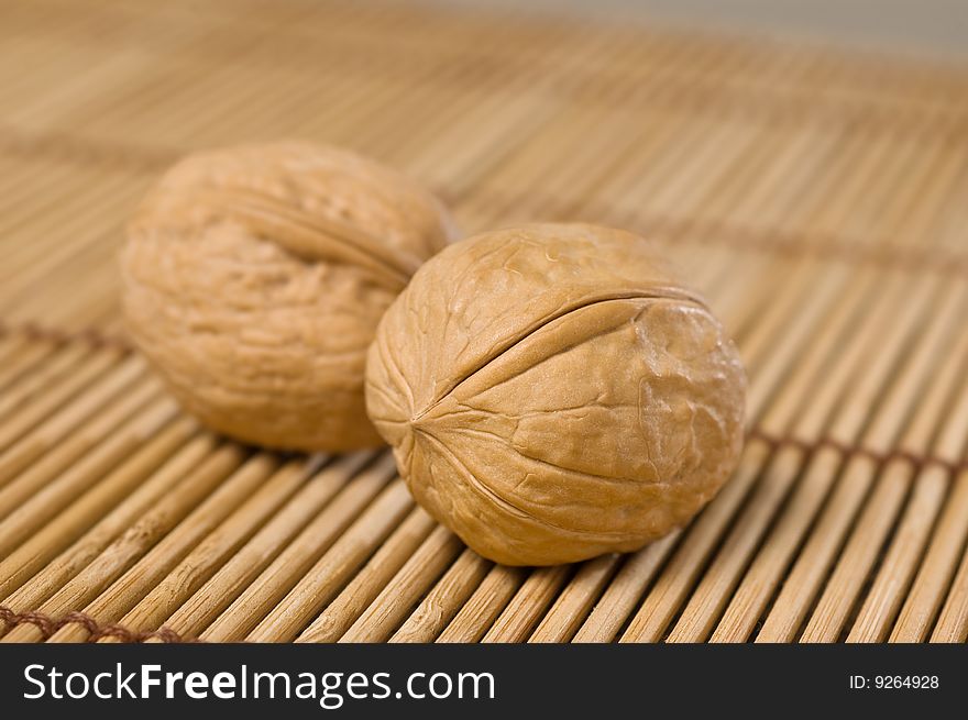 Two walnuts on bamboo mat.