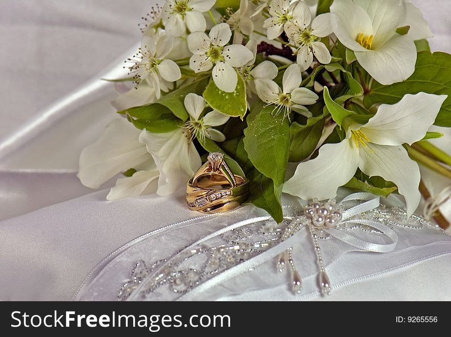 Spring blossom bridal bouquet and wedding rings on a satin pillow. Spring blossom bridal bouquet and wedding rings on a satin pillow.