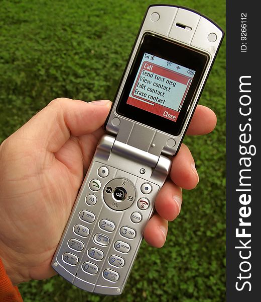 Photo of cell phone being used outdoors with lush spring time grass as a backdrop. Photo of cell phone being used outdoors with lush spring time grass as a backdrop.