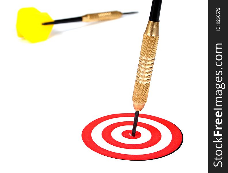 Yellow dart pinned to the center of a red target on a white background. Yellow dart pinned to the center of a red target on a white background
