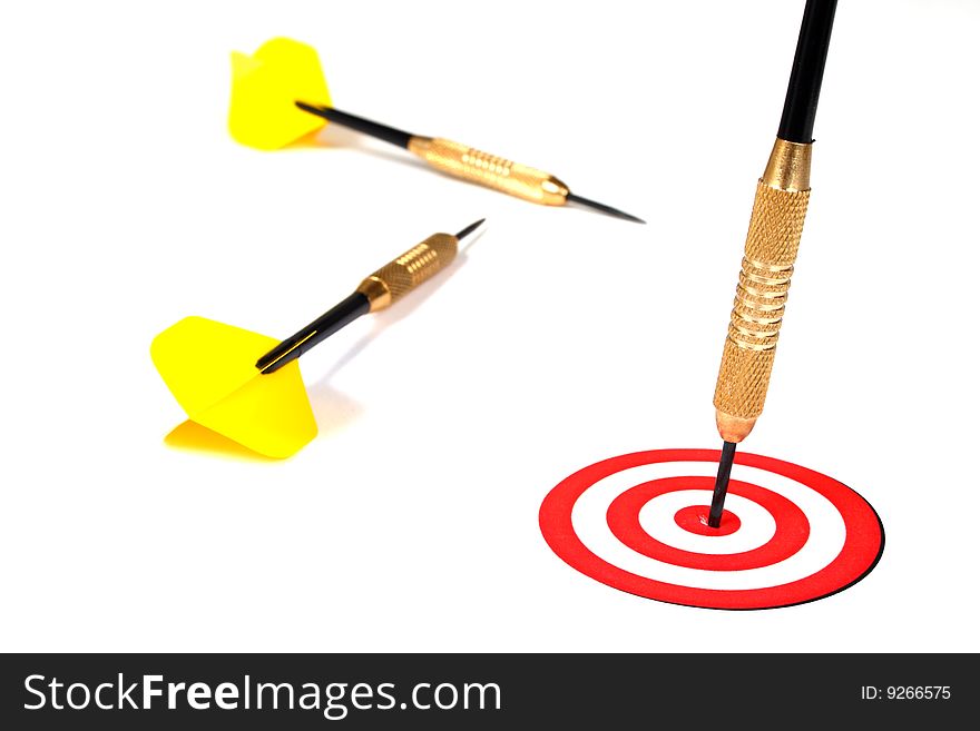 Yellow dart pinned to the center of a red target on a white background. Yellow dart pinned to the center of a red target on a white background