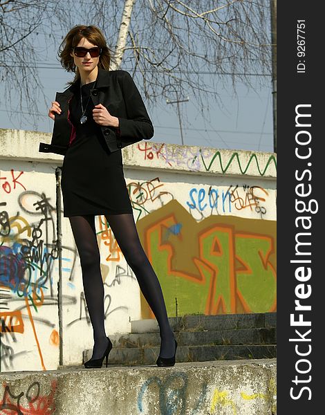 Business woman in sunglasses posing at the graffiti wall