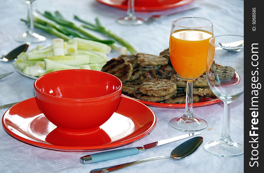 Red plates and orange juice served on table in kitchen. Red plates and orange juice served on table in kitchen