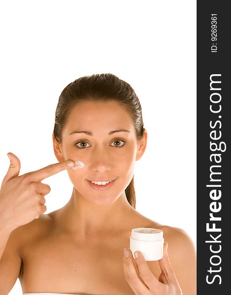 Nice attractiveyoung caucasian brunette applying cream on the face isolated on white.Concept of skincare. Nice attractiveyoung caucasian brunette applying cream on the face isolated on white.Concept of skincare