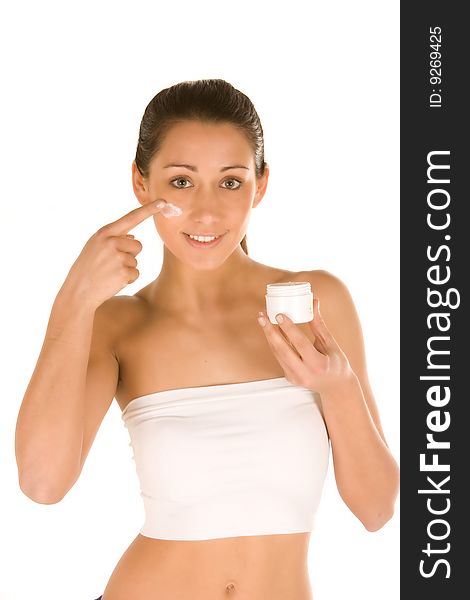 Nice attractiveyoung caucasian brunette applying cream on the face isolated on white.Concept of skincare. Nice attractiveyoung caucasian brunette applying cream on the face isolated on white.Concept of skincare