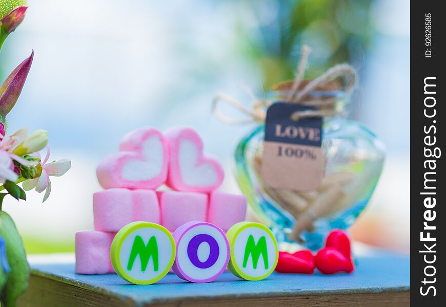 Mother`s day concept. MOM alphabet with marshmallow in the shape of heart and flower on background