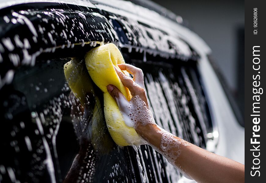 Woman Hand With Yellow Sponge Washing Car