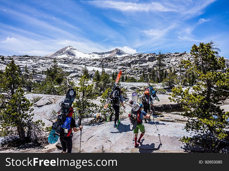 Group of People Hiking With Snowboards Under Blue Cloudy Sky