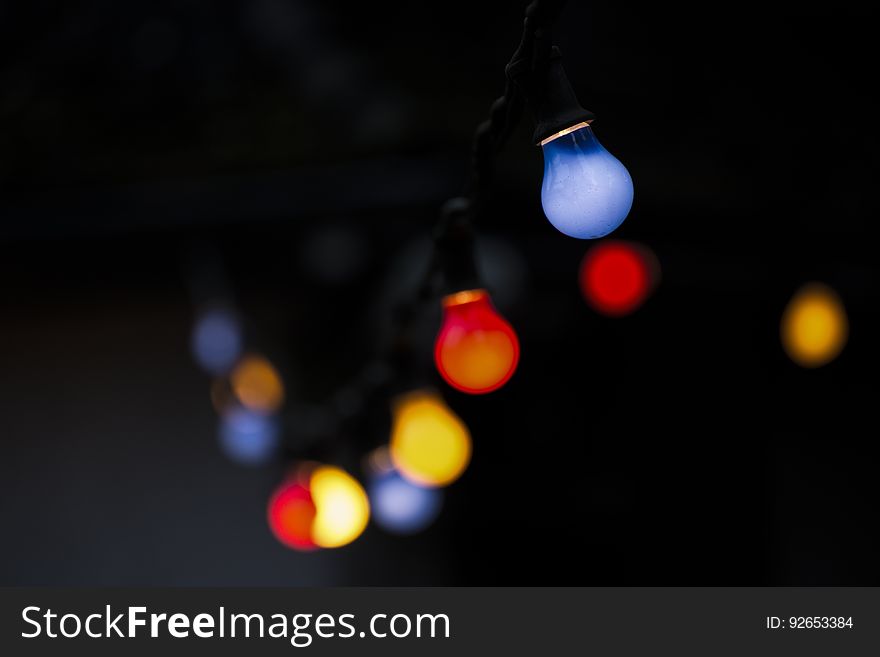 Blurred colored filament light bulbs with envelope in red, yellow orange, blue and brown, black background,. Blurred colored filament light bulbs with envelope in red, yellow orange, blue and brown, black background,