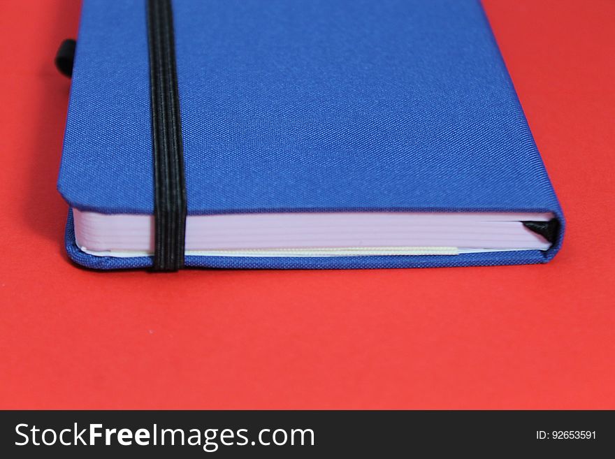 A blue notebook isolated against a red background.