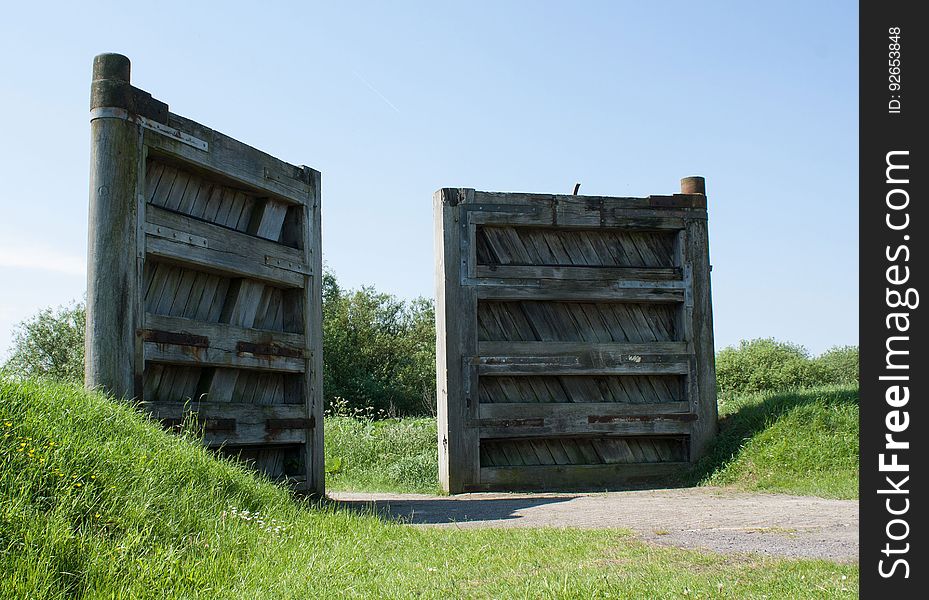 An opened wooden gate on a rural road.