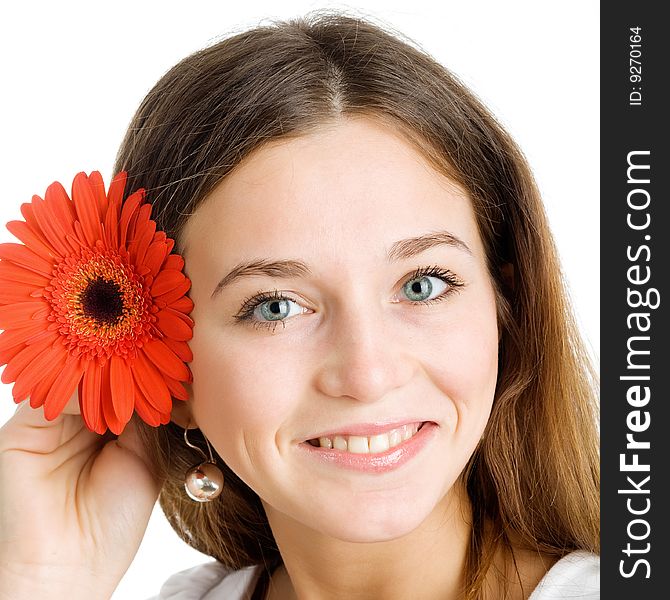 A smiling beautiful young woman in a white dress with a bright red flower near her face. A smiling beautiful young woman in a white dress with a bright red flower near her face