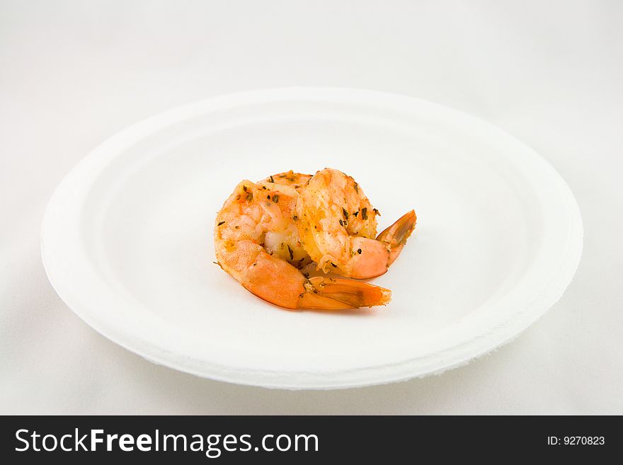 Two spicy pink prawns on a white plate with a white background. Two spicy pink prawns on a white plate with a white background