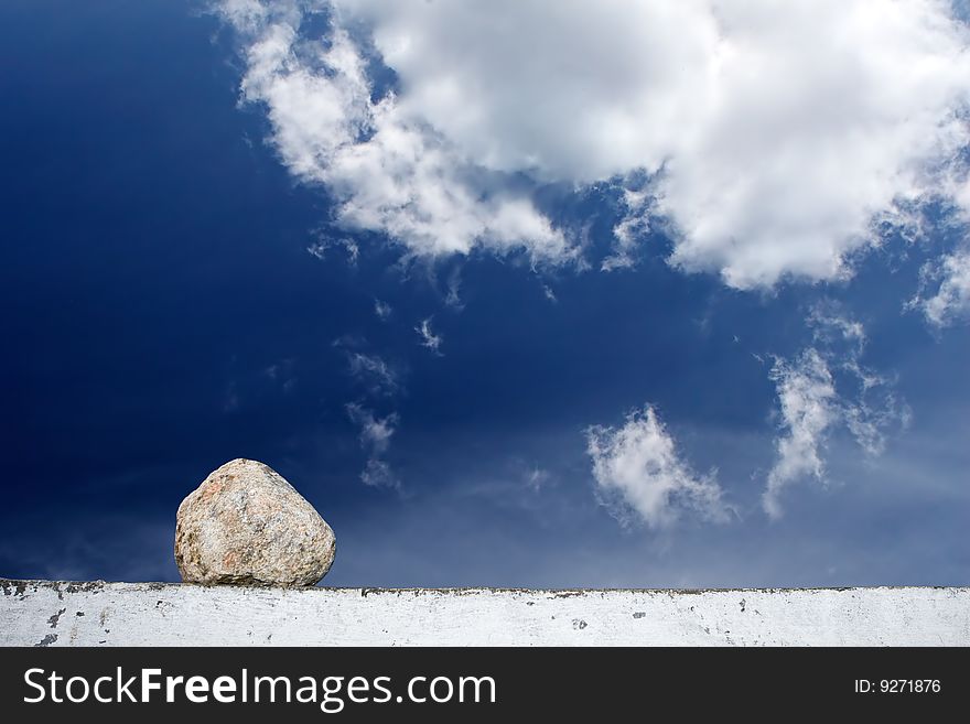 Stone on a stone plate against the blue sky with clouds. Stone on a stone plate against the blue sky with clouds