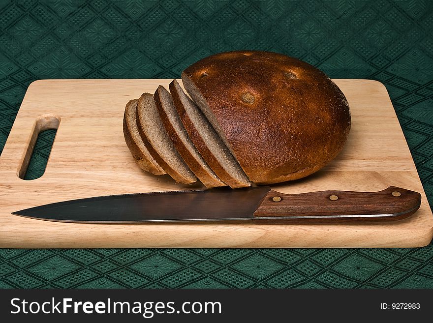 Brown bread and knife on a chopping board. Brown bread and knife on a chopping board