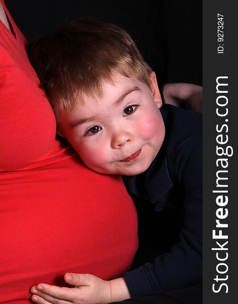 A young boy hugging his expecting mother's belly