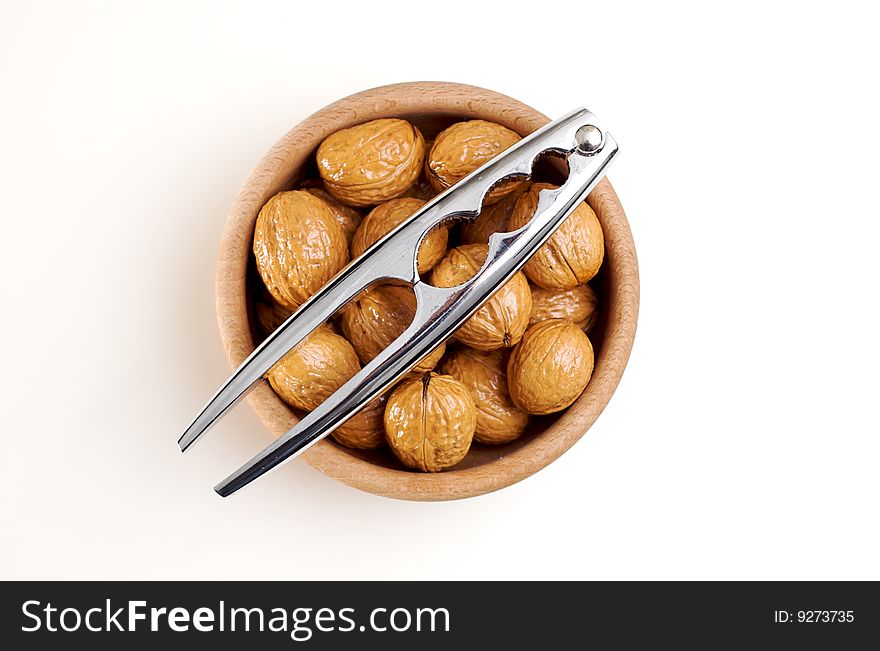 Bowl of walnuts and a steel nutcracker isolated on white. Bowl of walnuts and a steel nutcracker isolated on white