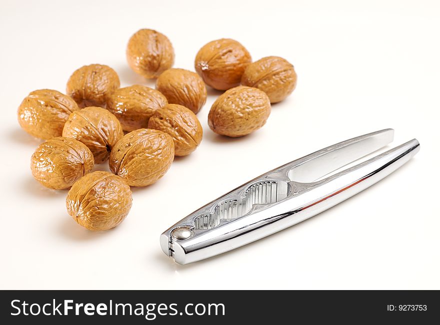 Walnuts and a steel nutcracker isolated on white. Walnuts and a steel nutcracker isolated on white