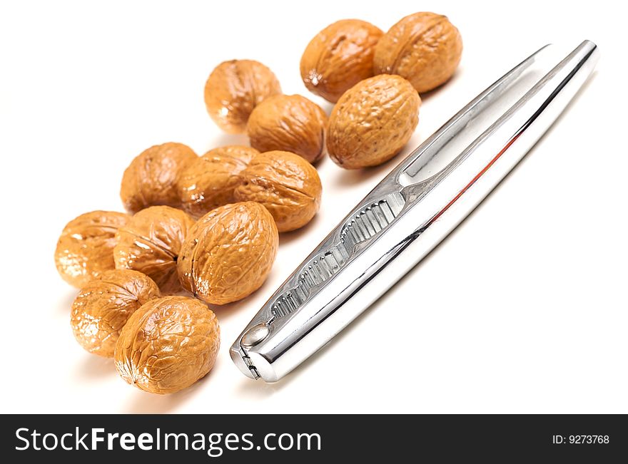 Walnuts and a steel nutcracker isolated on white. Walnuts and a steel nutcracker isolated on white