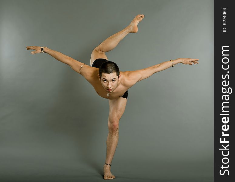 Young muscular dancer posing over gray background. Young muscular dancer posing over gray background