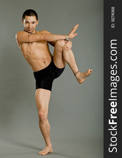 Young muscular dancer posing over gray background. Young muscular dancer posing over gray background