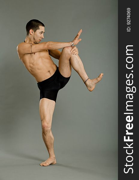 Young muscular dancer posing over gray background. Young muscular dancer posing over gray background